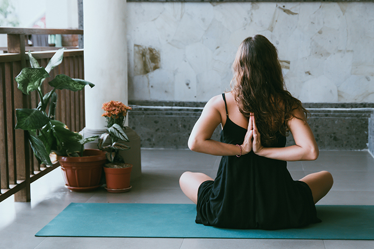Woman sitting down on a yoga mat doing a yoga pose