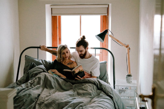 Image of a couple sitting in bed reading a book