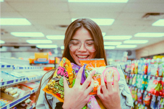 Woman in grocery store holding a selection of sweets